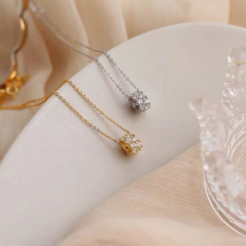 Gold and silver chain necklaces with sparkling cubic pendants on soft fabric background