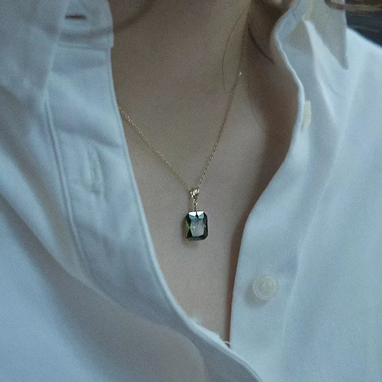 18K gold plated necklace with a faceted green gemstone pendant on a woman in a white shirt