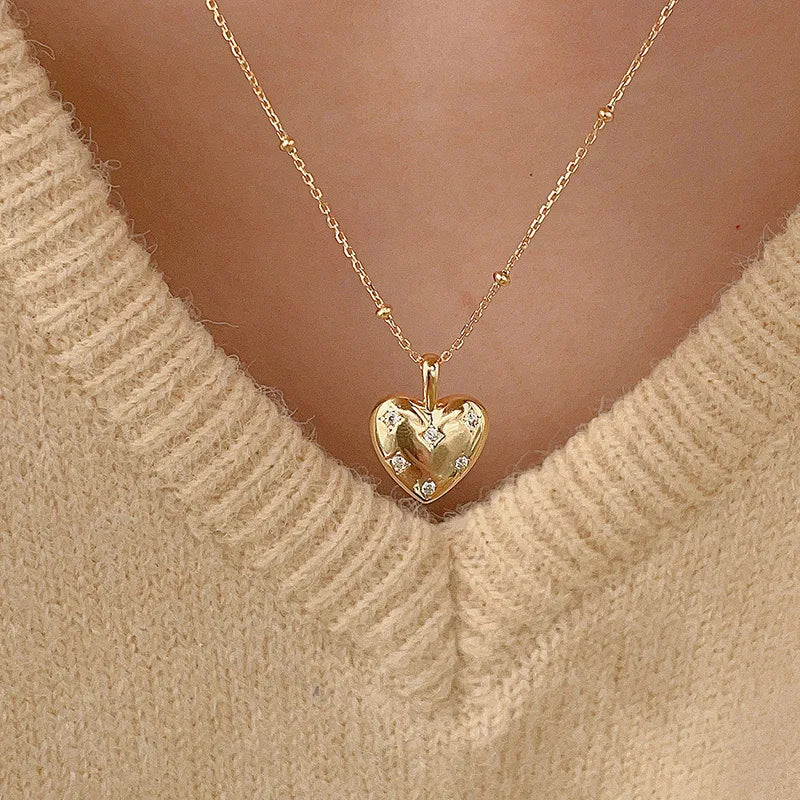 18K gold plated heart pendant necklace with cubic zirconia, worn on a cream sweater