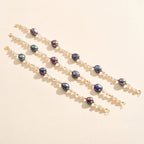 Four pearl beaded bracelets with black and white pearls and gold accents on beige background.