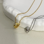 Gold and silver pendant necklaces with round charms and clear stones on a textured surface