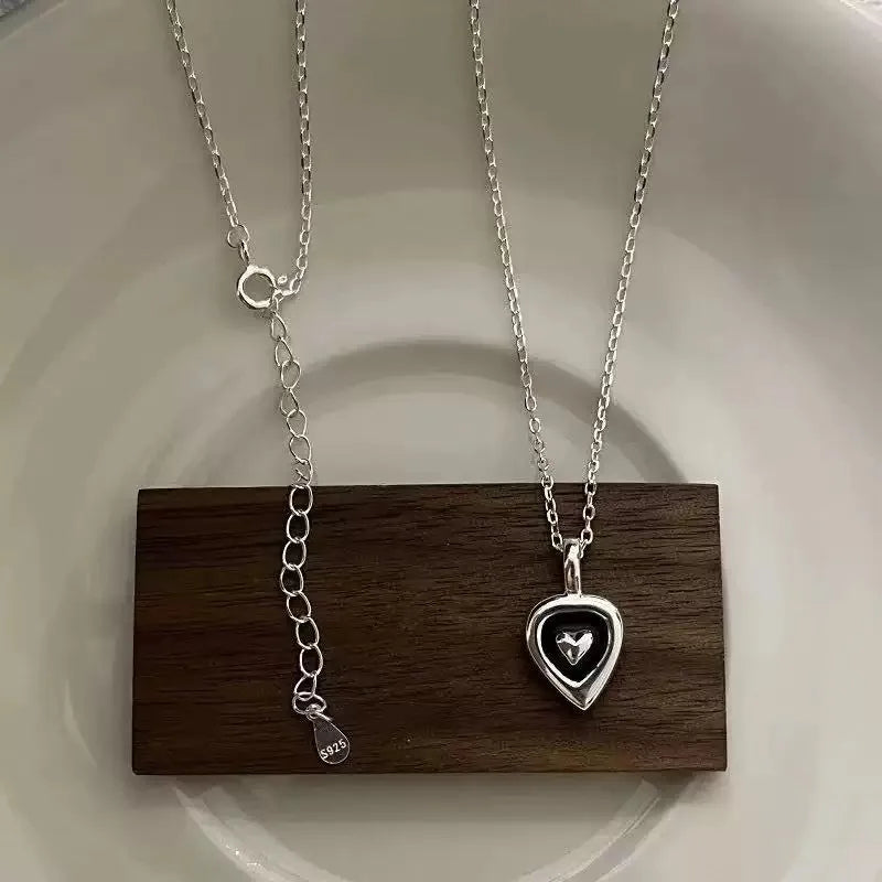 Sterling silver heart pendant necklace with adjustable chain on a dark wood display