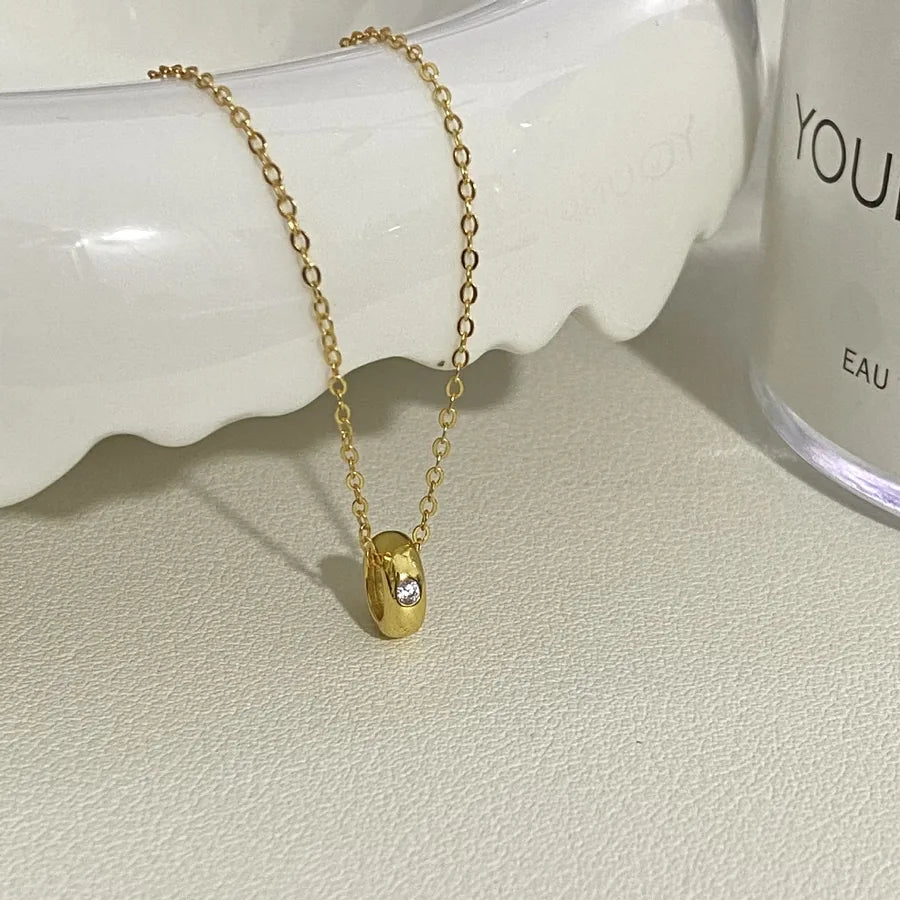 18K gold plated pendant necklace with a round crystal accent on a textured surface