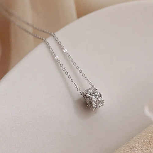 Delicate silver chain necklace with a pavé crystal cylinder pendant on a soft neutral background.