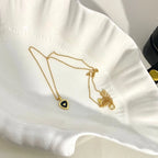 Gold heart pendant necklace with black center on a scalloped white dish