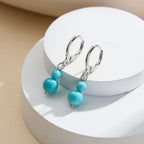 Silver leverback earrings with double turquoise beads, demi-fine jewelry on white display