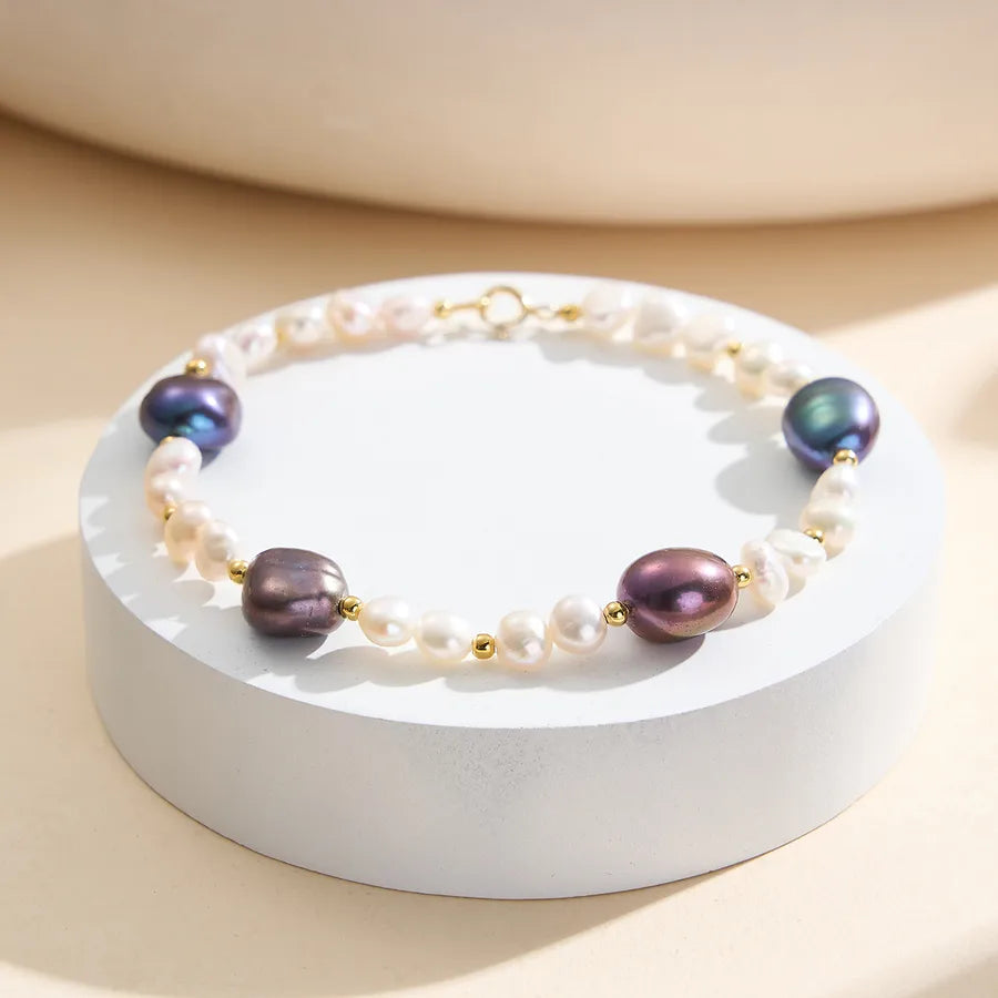 Colorful baroque pearl bracelet with gold beads on a round display, elegant jewelry