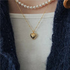 Layered necklaces with pearl choker and gold heart pendant on white ribbed top